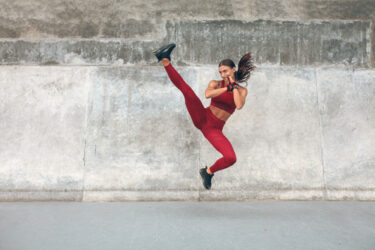 Fitness Girl Kicking.  Fit Female In Fashion Sportswear Doing Intense Exercise.