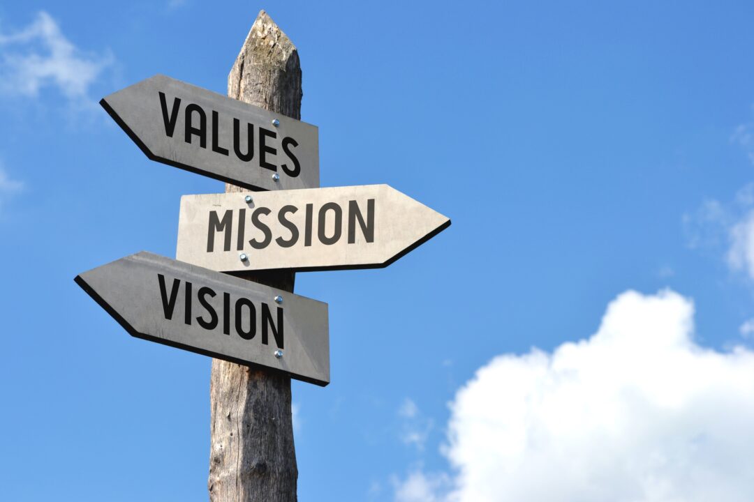 Wooden signpost showing value, vision, and mission.