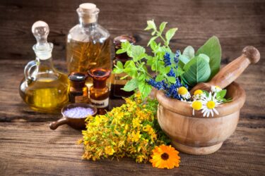 Essential oil, mortar with fresh herbs and bath salt on wooden background