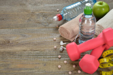 Dumbbell, water and towel on wooden background, fitness concept