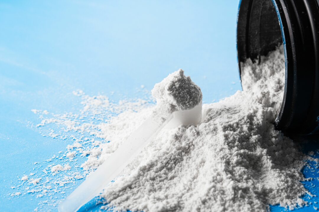 a scoop of spilled creatine on a blue background.