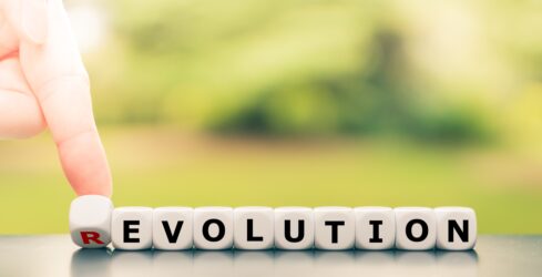 Evolution instead of revolution. Hand turns a dice and changes the word "revolution" to "evolution".