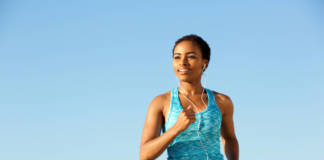 Portrait of happy young fitness woman running with earphones