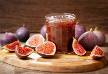 glass jar of figs jam with fresh fruits on wooden table