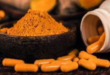 Curcumin herbal supplement capsules and turmeric powder in glass bowl. Anti-inflammatory herbal medicine (Curcuma)