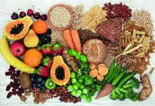 Food with high fiber content for a healthy diet with fruit, vegetables, whole wheat bread, pasta, nuts, legumes, grains and cereals. High in antioxidants, anthocyanins, vitamins and omega 3 fatty acid. Rustic background top view.