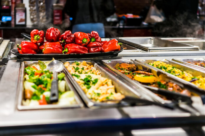 Buffet bar and trays with roasted salad vegetables, red bell peppers and meat dishes