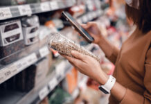 Closeup - Woman shopping in supermarket and reading product information. Costumer buying food at the market.