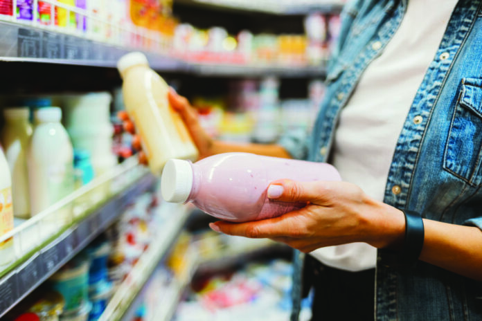 Close-up of bottled dairy products in female hands at grocery store