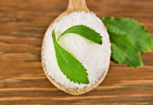 Stevia leaves with sugar in a wooden spoon on a wooden background