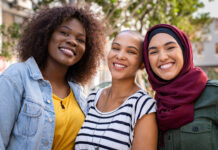 Group of three happy multiethnic friends looking at camera. Portrait of young women enjoying vacation together
