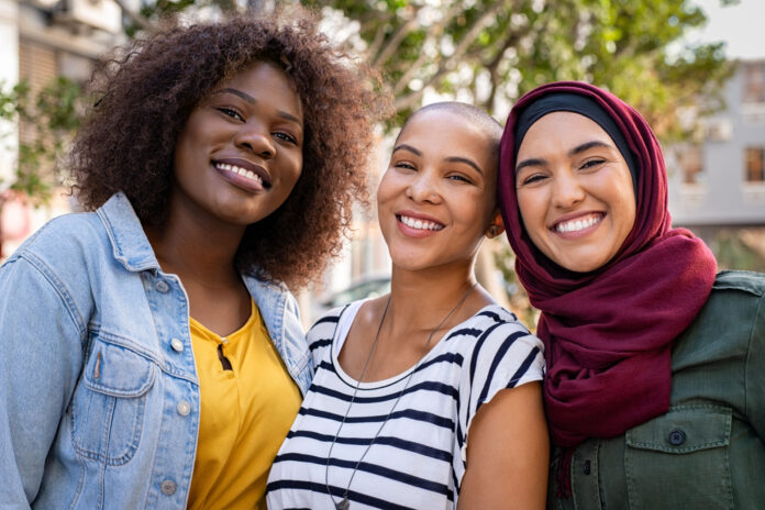 Group of three happy multiethnic friends looking at camera. Portrait of young women enjoying vacation together