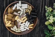 Multivitamin pills on a clay plate, on a vintage wooden table, with a sprig of mint