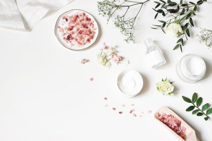 Styled beauty corner, web banner. Skin cream, tonicum bottle, dry flowers, leaves, rose and Himalayan salt. White table background. Organic cosmetics, spa concept